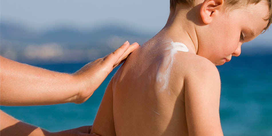 mother applying sunscreen to her son's back