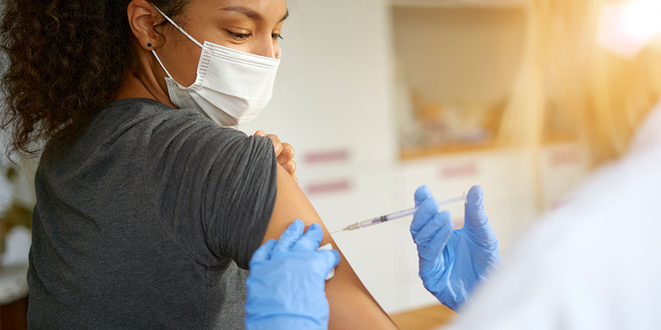 Young woman getting a shot in her upper arm.