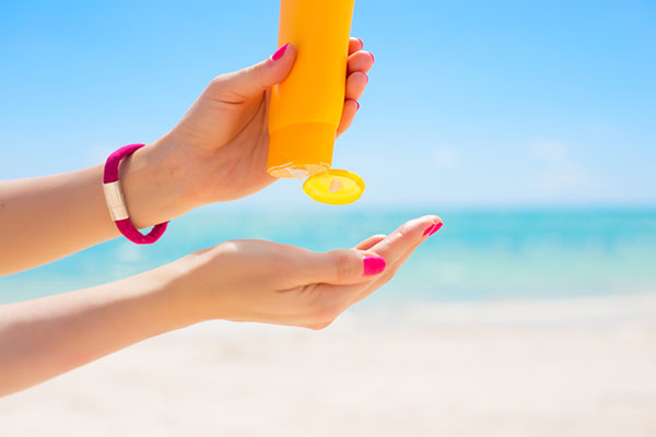 woman squeezing a tube of sunscreen into her hand
