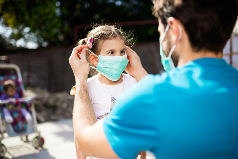 adult helping child put-on face mask