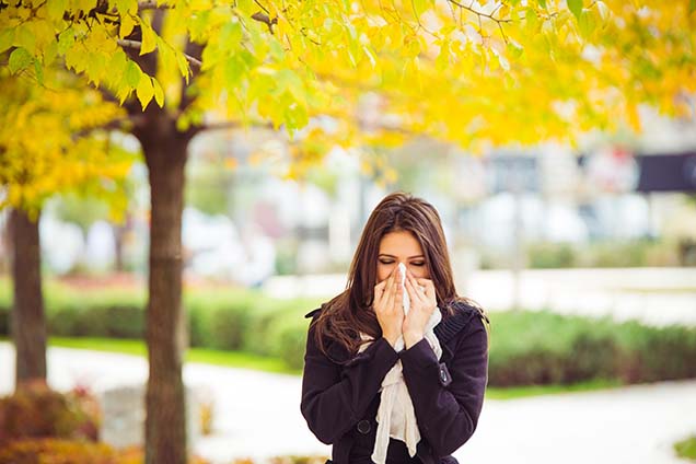 Woman blowing nose from fall allergy symptoms